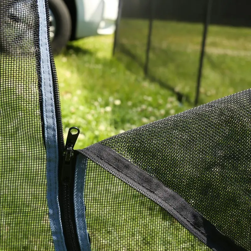 Mobiler Hundezaun your GEAR Larino mit schwarzem Netzgewebe, Reißverschluss-Verbindung und stabilem Rahmen, aufgebaut auf grünem Rasen, ideal für Camping oder Garten, im Hintergrund ein Wohnmobil.