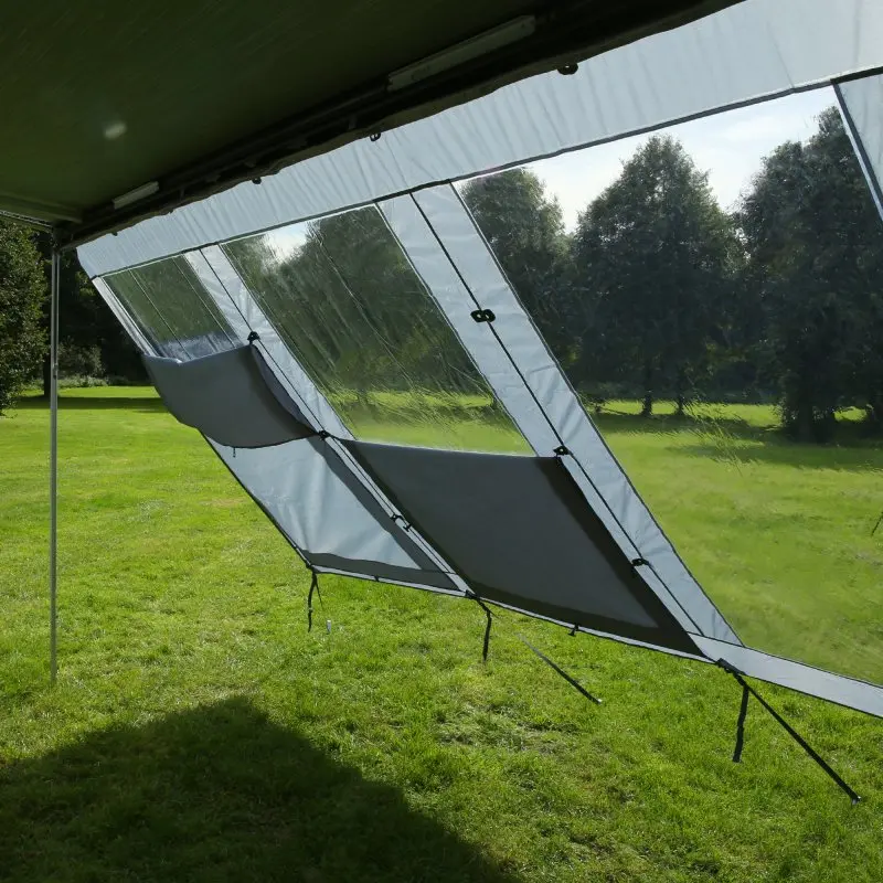 Pared frontal your GEAR Panorama Wall de 2,4 x 2 m colocada en una marquesina, con paneles transparentes y secciones opacas, protege del sol, viento y lluvia en un entorno al aire libre.
