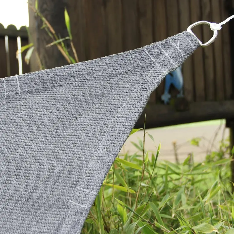 Coin du voile d'ombrage yourGEAR 3x3 m en tissu HDPE gris, texture aérée, anneau métallique de fixation visible, adapté pour terrasse ou jardin, protection solaire et perméabilité à l'air.