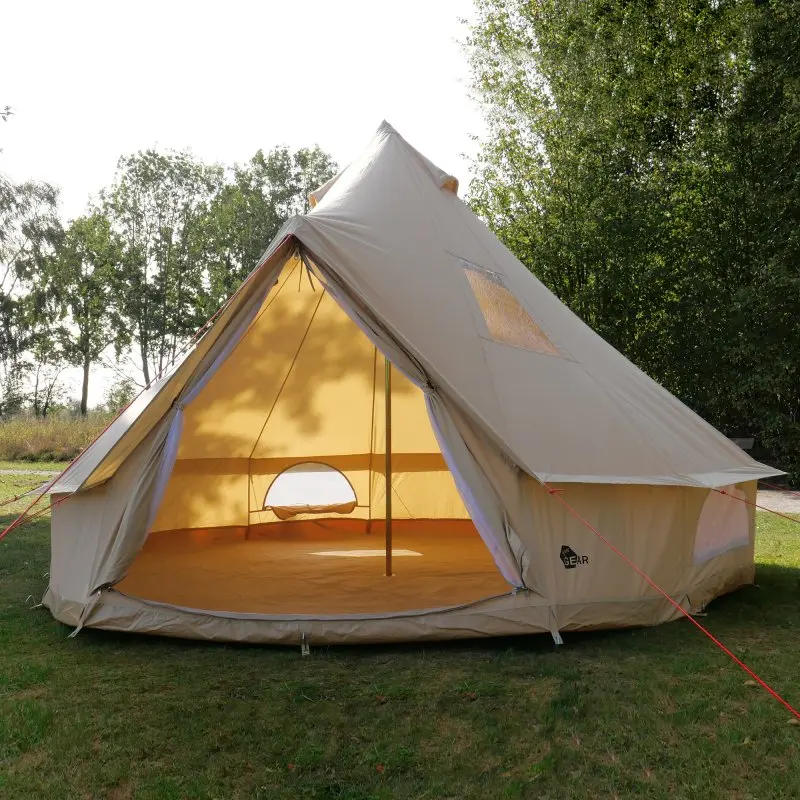 Tipi-Zelt your GEAR Desert 8 Pro aus sandfarbenem Baumwoll-Mischgewebe, mit großem Eingang, wannenförmigem Zeltboden, Fenster und Rund-Um-Insektenschutz, auf einer Wiese aufgebaut.
