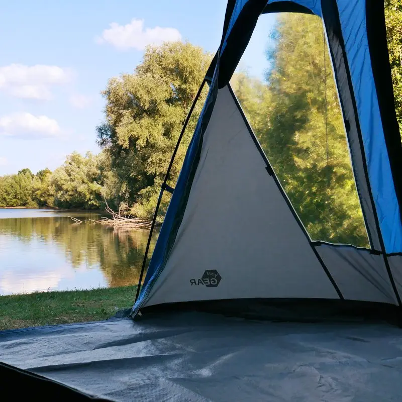 Tente your GEAR Tivano 5 personnes, forme dôme, couleur bleu et gris, grande hauteur sous plafond, grande entrée latérale, fenêtre transparente, sol séparé, installée près d’un lac en pleine nature.