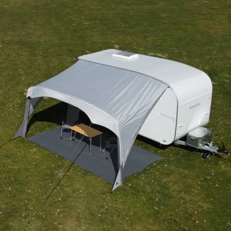 Graues your GEAR Amalfi Air 450 Sonnensegel als aufblasbares Vorzelt an einem weißen Hobby Beachy Wohnwagen, maßgeschneidert, mit Tisch und Stühlen darunter, auf grünem Rasen aufgestellt.