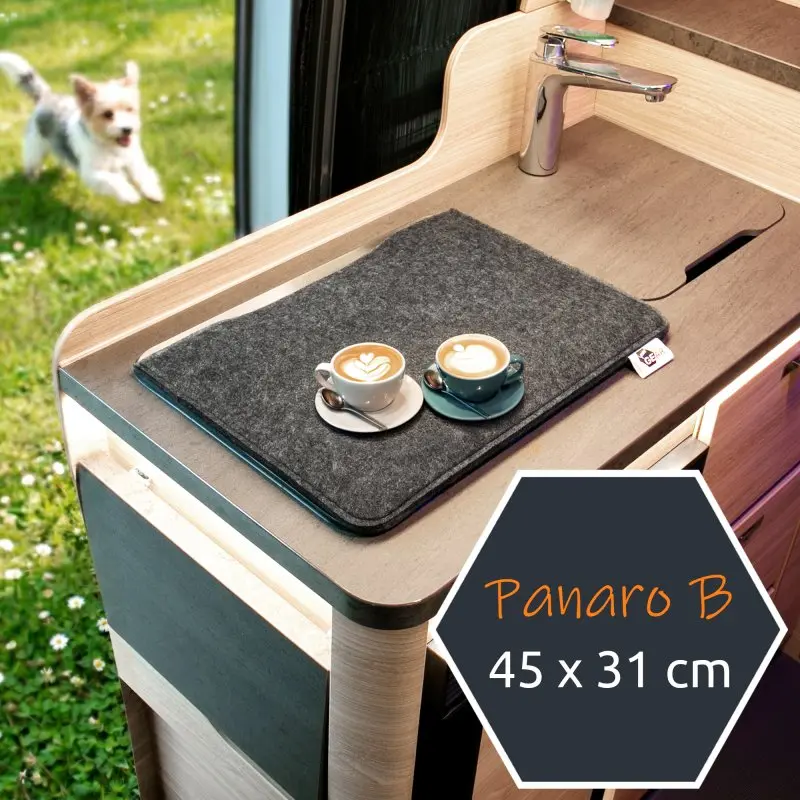Cubierta de fieltro gris your GEAR Panaro B de 45 x 31 cm sobre fregadero en cocina de caravana, utilizada como protección silenciosa para hornos y fregaderos, con dos tazas de café encima.