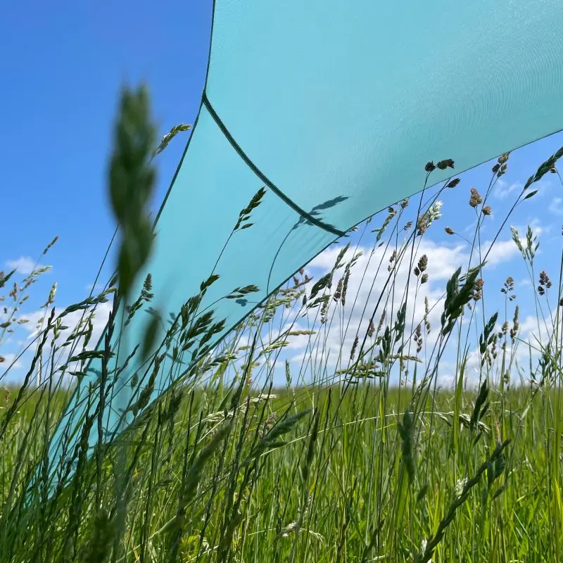 XXL your GEAR Cameo beach shelter 3x3m in turquoise, set up as a sunshade on a grassy field under blue sky. Lightweight Lycra fabric provides UV 50+ protection, ideal for outdoor use.