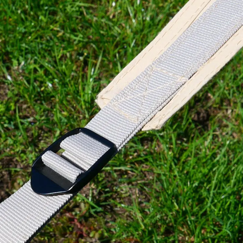 Sangle de fixation robuste du pavillon your GEAR Sonora, en tissu mélangé coton, avec boucle noire pour l’ancrage au sol, posée sur de l’herbe. Accessoire essentiel pour la stabilité du grand auvent étoile.