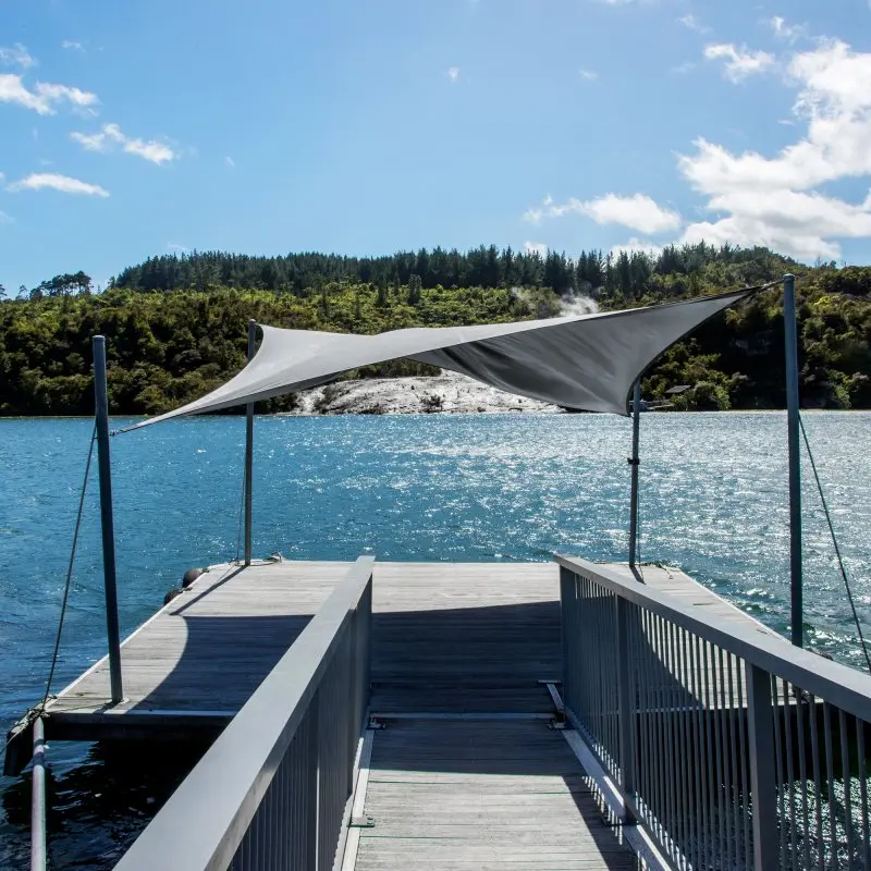 Voile d'ombrage yourGEAR gris 3x3 m en HDPE, installée sur un ponton au bord de l’eau, offrant une protection solaire UV, matériau perméable à l’air et à l’eau, adaptée terrasse, jardin ou camping.