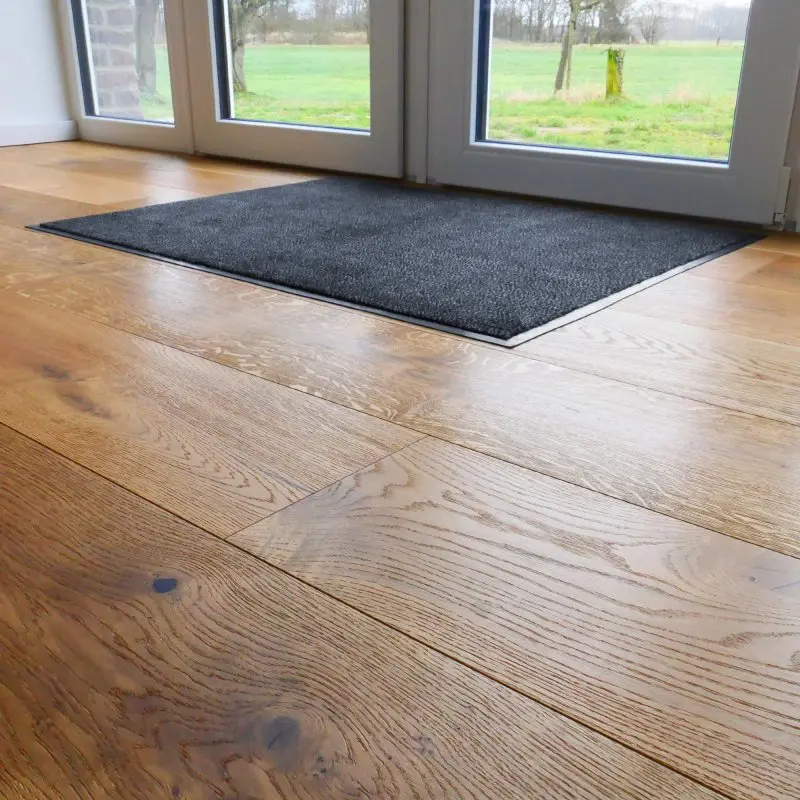 Schmutzfangmatte yourGEAR 120x90cm in Anthrazit, rechteckig, dichter Velours-Floor, rutschfest, mit Anlaufkante, auf hellem Holzboden vor einer Terrassentür, geeignet für innen und außen.