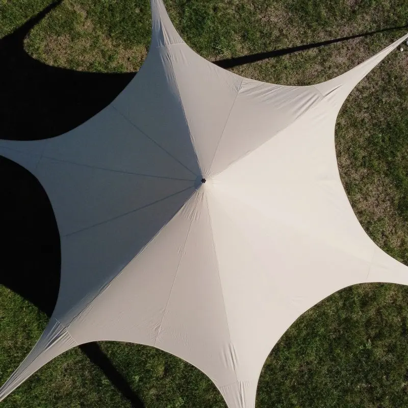 Vue aérienne du pavillon your GEAR Sonora, tente étoile de 10 m de diamètre en toile beige, installée sur l’herbe, avec six points d’ancrage visibles et structure pyramidale au centre.