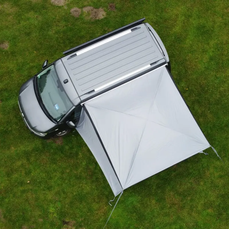 Auvent your GEAR Parasol de 2,6 x 2,6 m monté sur un van gris, offrant une grande zone d’ombre avec armature stable sur pelouse, idéal pour camping-car et VW Multivan.