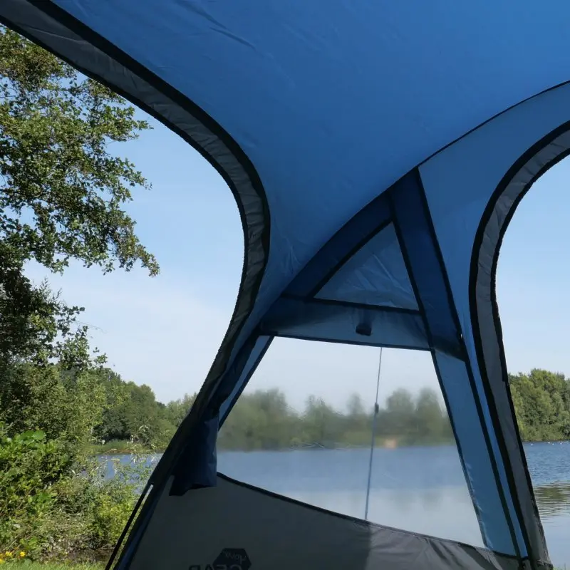Blau-graues yourGEAR Kuppelzelt Posada 4 für 4 Personen, mit großem Vorbau, verschließbarem Fenster und seitlichem Eingang, Blick nach außen auf See und Bäume, wasserdicht bis 3000 mm.