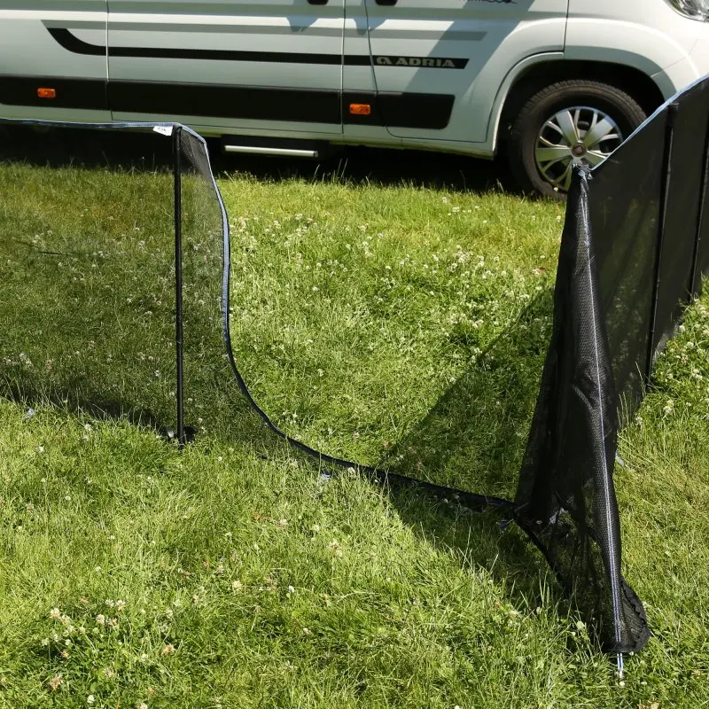 Mobiler Hundezaun your GEAR Larino, 90 cm hoch, mit schwarzem Netzmaterial und stabilen Stangen, auf grüner Wiese vor einem Wohnmobil aufgebaut, flexibel erweiterbar durch Reißverschluss-System.