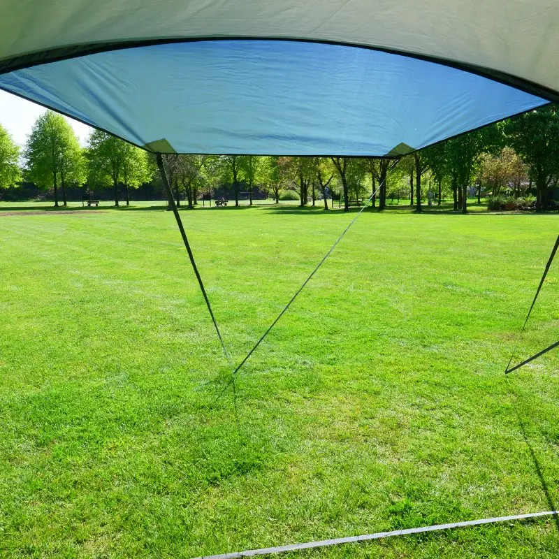 Auvent de bus your GEAR Panarea 320, toile imperméable, protection UV 50+, grande surface d’ombrage, structure légère, monté sur une pelouse avec haubans visibles, idéal pour camping en van.