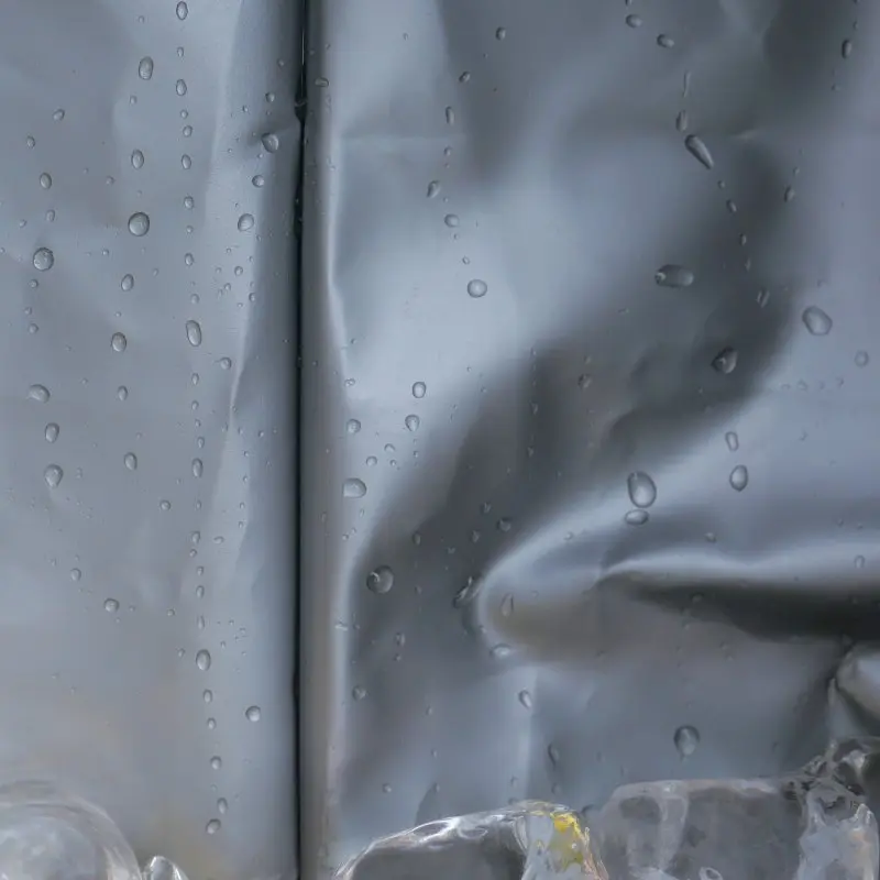 Close-up of the waterproof, food-safe PEVA insulation liner of the your GEAR Cavoli 30L foldable cooler bag, showing water droplets and ice, highlighting its robust and easy-to-clean material for effective cooling.