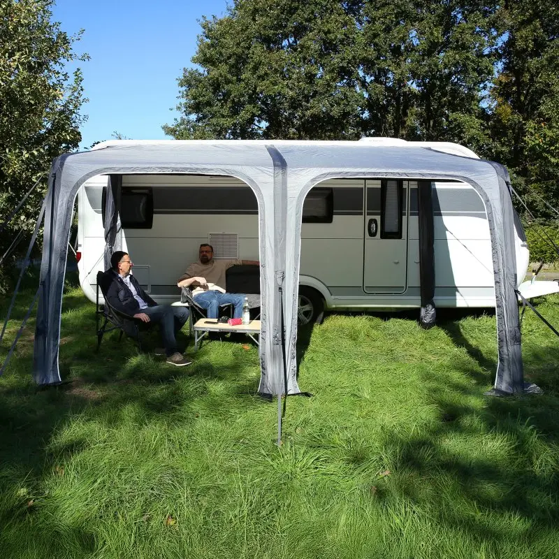 Auvent gonflable your GEAR Porto 420 Air monté sur une caravane, offrant un espace ombragé et protégé, deux hommes assis sous l’auvent, structure grise avec grandes ouvertures, usage camping.