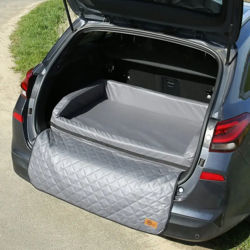 Grau gepolstertes your GEAR Kofferraum-Hundebett Termoli 100 x 70 cm mit erhöhten Seitenwänden und fest angenähtem Ladekantenschutz, ausgelegt im Kofferraum eines Autos. Ideal für Komfort und Schutz beim Hundetransport.