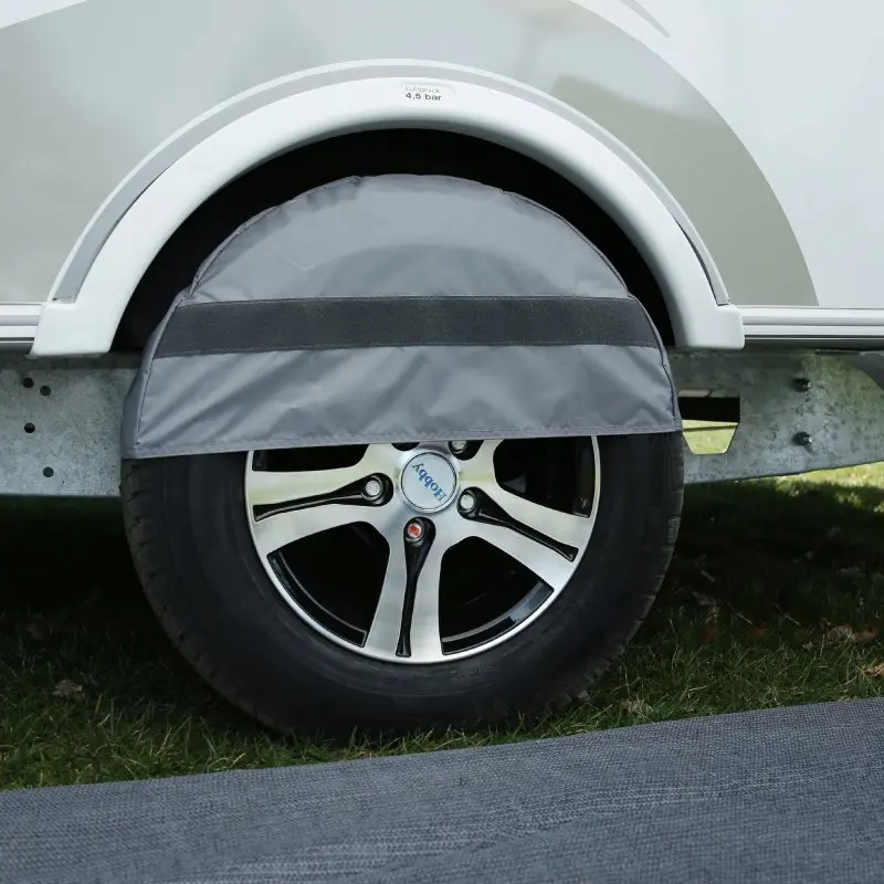 Jupe de roue your GEAR Brela 360 grise montée sur une caravane Hobby Beachy 360, couvrant partiellement la roue pour protéger contre le vent et améliorer l’isolation du auvent lors du camping.
