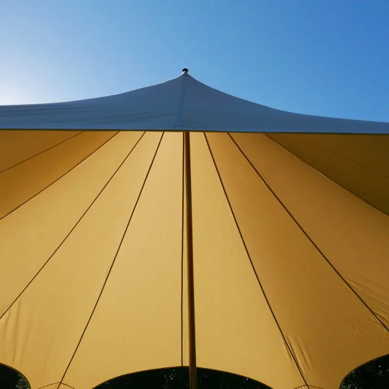 Tente étoile your GEAR Sonora Ø 10 x 4 m, pavillon beige en toile coton mélangé, forme pyramidale avec mât central robuste, offrant une large zone d’ombre sous un ciel bleu. Protection solaire extérieure.