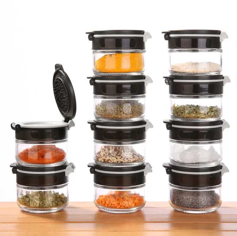 Set de 10 pots à épices your GEAR Double-Flip, en verre, 85 ml chacun, couvercles noirs à double ouverture, empilables, idéal pour le rangement des épices en cuisine, un couvercle ouvert visible.