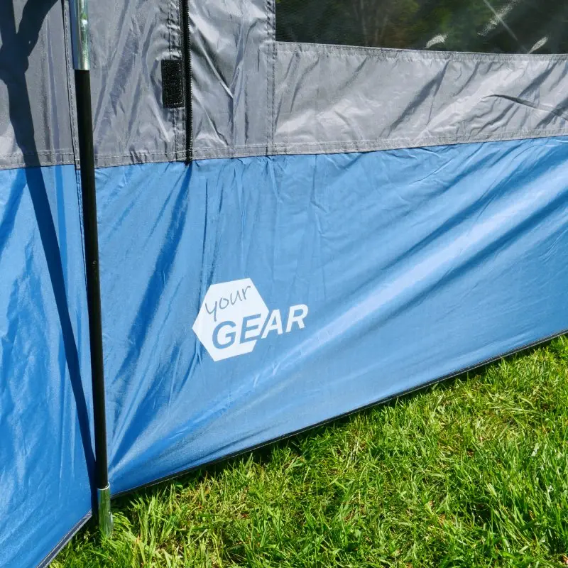 Detailaufnahme des your GEAR Panarea 320 Busvorzelts in Blau und Grau, mit sichtbarem Logo auf der Zeltwand, stabilem Gestänge und wasserdichtem Material auf grünem Rasen. Ideal für Busse und Camper.
