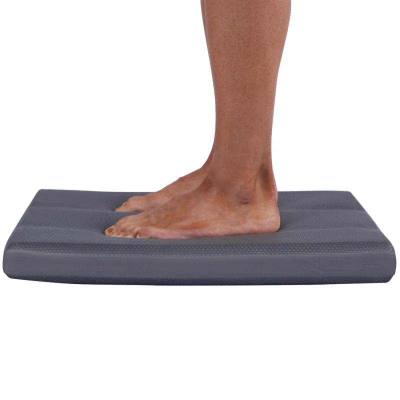 Persona in piedi su un cuscino equilibrio Spirit Balance-Block XL grigio, rettangolare, dimensioni 50x40x6 cm, ideale per esercizi yoga, fitness e allenamento della stabilità e coordinazione.