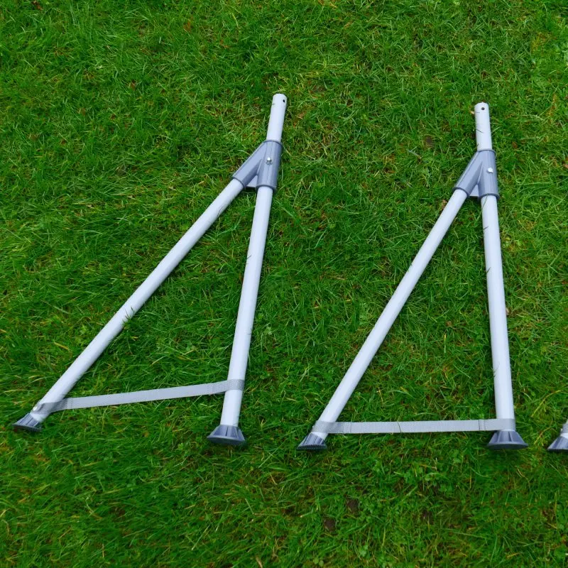 Deux supports de cadre en acier tubulaire gris du yourGEAR piscine familiale 3x2x0,7m, posés sur de l’herbe, illustrant la structure stable du bassin de jardin rectangulaire.