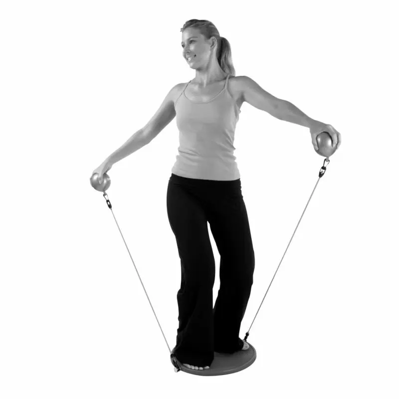 Donna su Carnegie IsoDisc Balance Pilates Board con Expander Tubes e due palle pesi, esegue esercizi di equilibrio e forza. Perfetto per allenamento Pilates, riabilitazione e rafforzamento muscolare.