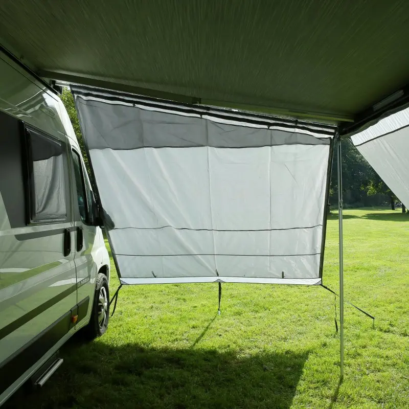 Pared lateral your GEAR Sun + Rain Blocker montada en una caravana, protege del sol, viento y lluvia; tela gris claro, estructura con barras metálicas. Ideal para toldos de 250 cm en campers y autocaravanas.