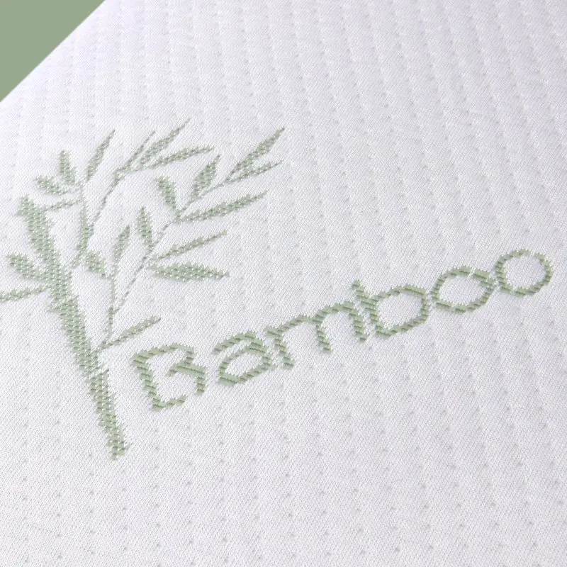 Cuscino ortopedico yourGEAR in memory foam con rivestimento ipoallergenico in bambù, dettaglio della superficie bianca con ricamo verde di ramo di bambù e scritta "Bamboo", dimensioni 60x35x11,5 cm.