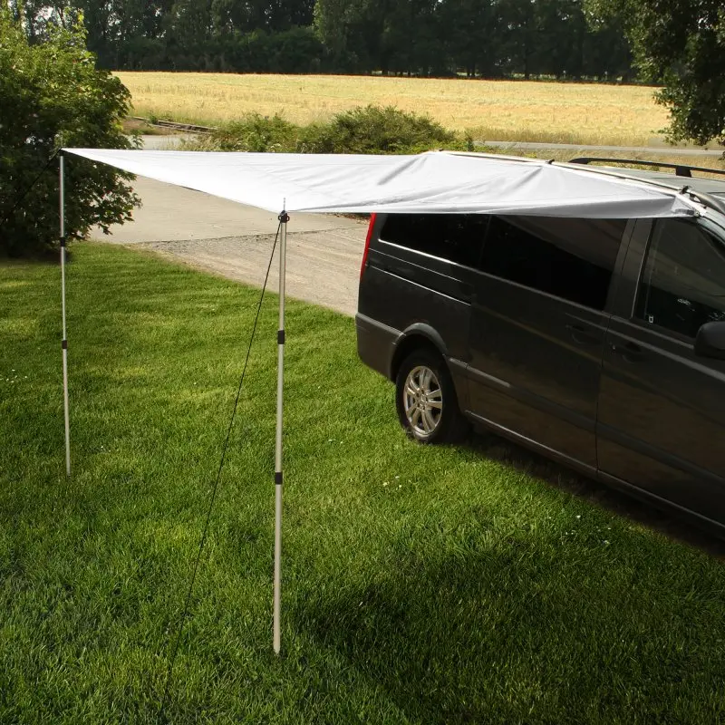 Toldo para autocaravana yourGEAR de 260 x 240 cm en gris, instalado junto a una furgoneta. Incluye dos postes telescópicos de aluminio, ideal como protección solar y contra la lluvia en camping.