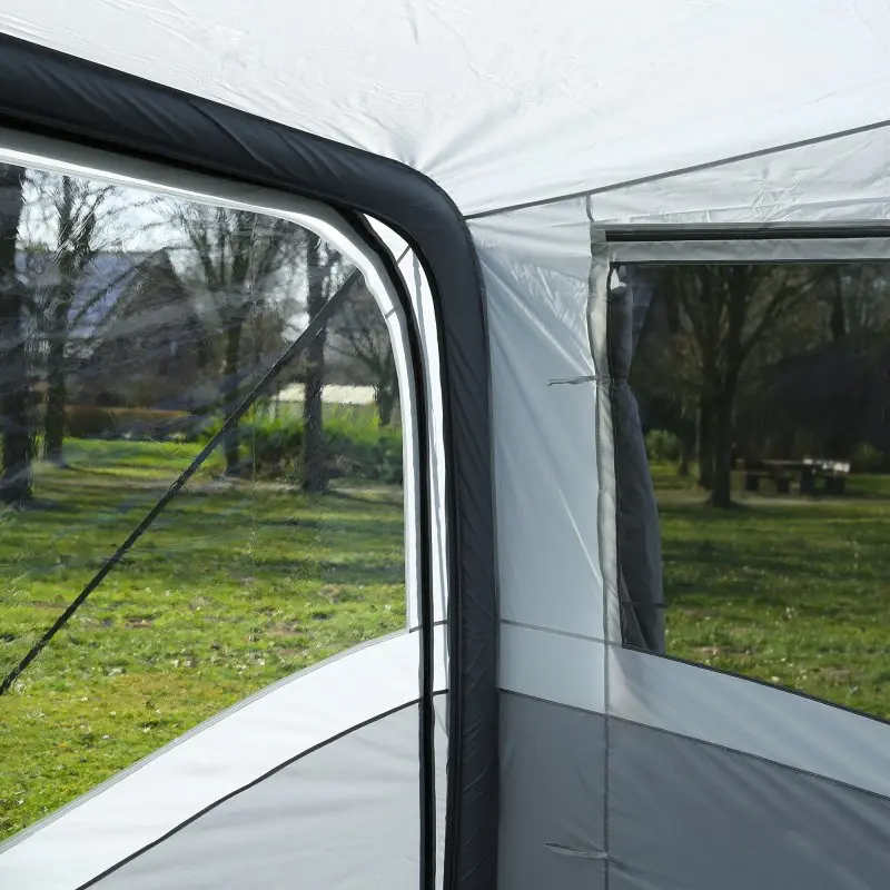 Vista dall’interno di una tenda con finestre trasparenti, che mostra un prato verde e alberi all’esterno.