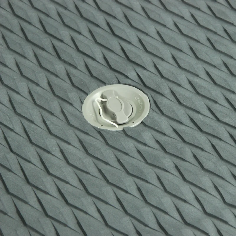 Valve grise sur une surface texturée en caoutchouc, probablement d’un paddle gonflable ou d’un matelas pneumatique.
