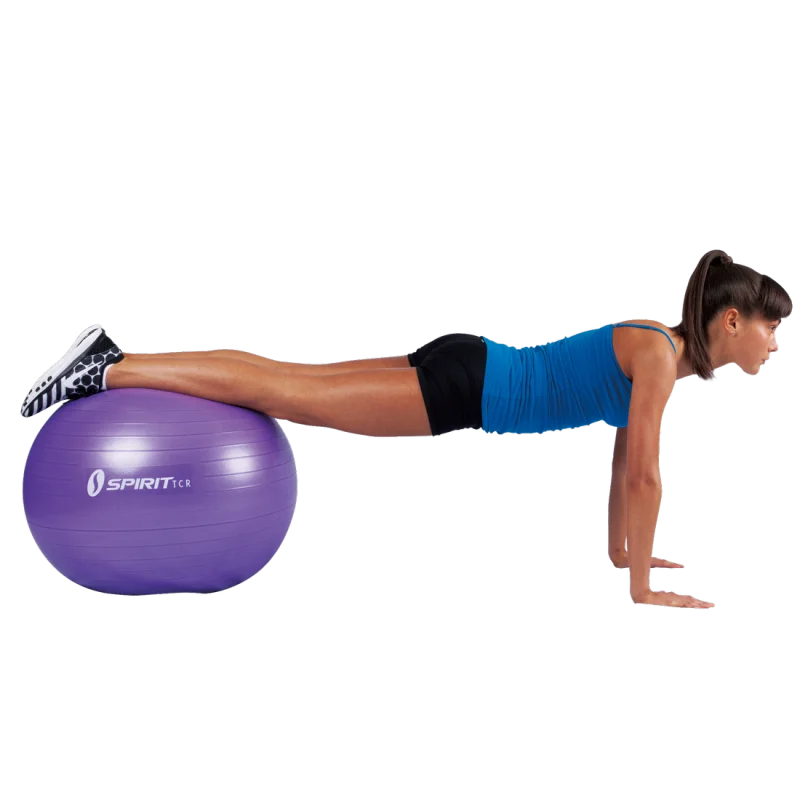 Woman exercising with Spirit TCR 65 cm purple gym ball; durable fitness ball ideal for yoga, pilates, and office use, shown supporting legs during a core workout. Fitness accessory for balance and strength training.
