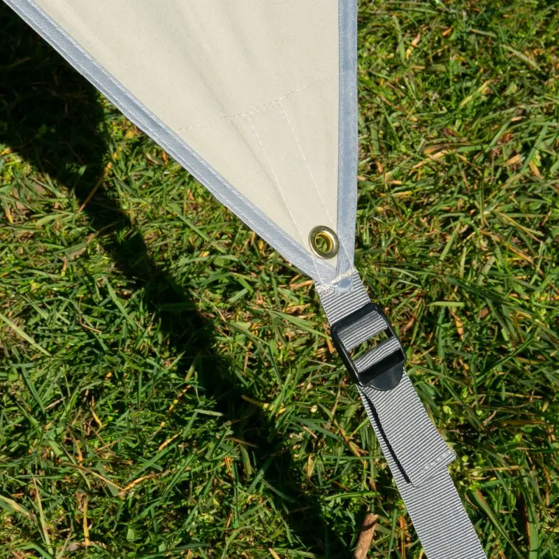 Angolo del telo your GEAR Tropea TC per camper, in tessuto misto cotone beige con occhiello in metallo e cinghia di fissaggio regolabile, steso su prato verde. Ideale come tenda parasole UV 50+ per van e bus.