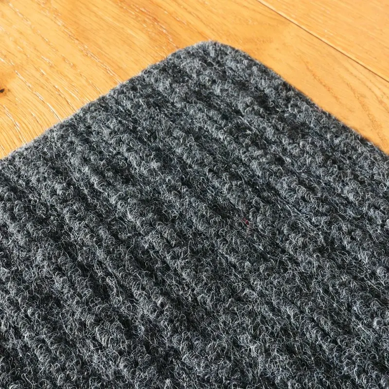 Tapis de marche d’escalier yourGEAR gris clair, surface en textile antidérapant, coins arrondis, texture bouclée, dimensions 76x20 cm, posé sur un sol en bois, idéal pour sécuriser les escaliers.