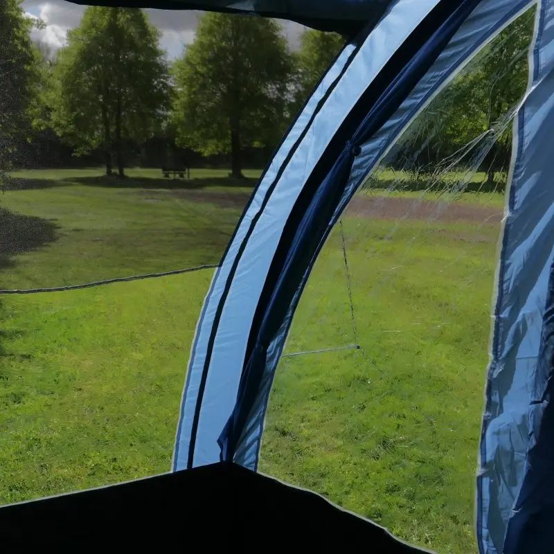 Vue de l'intérieur du tunnelzelt your GEAR Mistral 5 personnes, grandes fenêtres transparentes, tissu bleu clair, offrant une vue dégagée sur un espace vert, idéal pour le camping en famille.