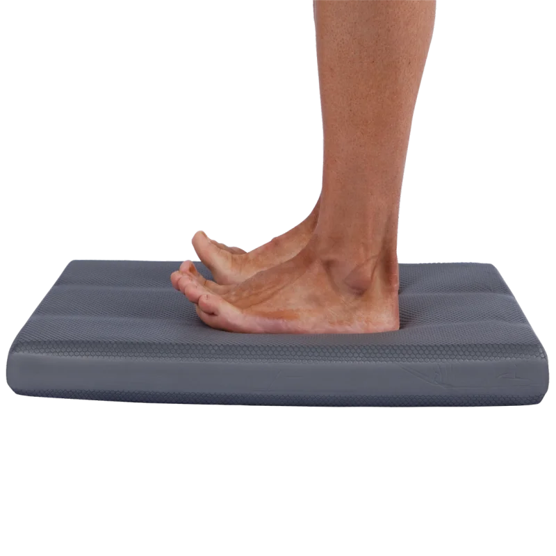 Spirit Balance-Block XL Balance Cushion 50x40x6 cm in Grau, rechteckig, mit strukturierter Oberfläche; eine Person steht barfuß auf dem Balance Trainer. Ideal für Yoga, Fitness und gelenkschonendes Training.