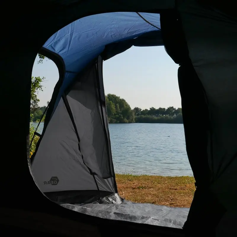 View from inside the your GEAR Sopero 4-person tunnel tent, showing the spacious side entrance, large vestibule area, and durable waterproof material with a scenic lake outside. Ideal for camping and trekking.