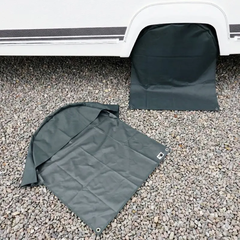 Coppia di copriruote grigio scuro yourGEAR per caravan e camper (16/17"), tessuto resistente con occhielli metallici, protezione UV, una copertura montata sulla ruota e l'altra distesa su ghiaia.