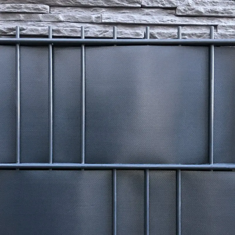 Sichtschutzstreifen aus dunkelgrauem, gewebeverstärktem PVC in Doppelstabmattenzaun montiert, strukturierte Oberfläche, robuste Optik, ideal für Zaun-Sichtschutz und Privatsphäre im Garten.