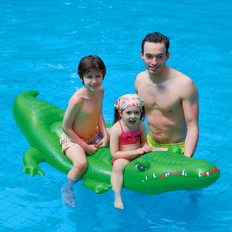 Colchón inflable Jilong en forma de cocodrilo XL de 200x100 cm, flotando en piscina con dos niños sentados sobre él y un adulto al lado. Incluye dos asas visibles para mayor seguridad.