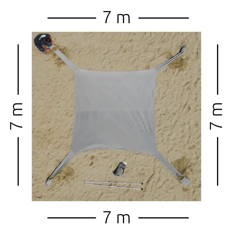 Grande voile de plage carrée grise your GEAR Cameo 3x3 m en Lycra tendue sur le sable, quatre sangles d'ancrage aux coins, deux mâts détachés et sac de transport visibles, protection UV et design léger et compact.