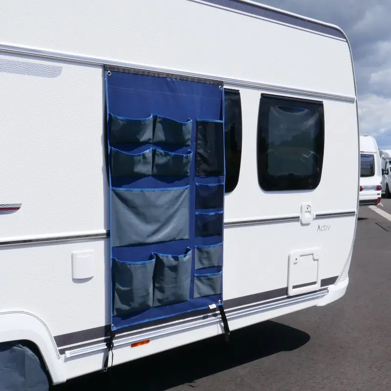 Organisateur suspendu your GEAR Caravan Tablet bleu, 140 x 85 cm, avec 12 poches visibles, fixé à la paroi d’une caravane. Idéal pour le rangement au camping ou en voyage, pratique et modulable.