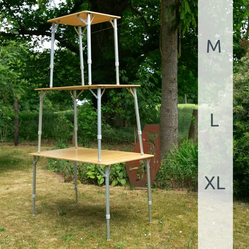 Bambus Campingtisch your GEAR Portofino M mit 3-fach höhenverstellbaren Teleskopbeinen, rechteckige Tischplatte aus Bambus, Beispiele für verschiedene Höhen (M, L, XL) im Garten dargestellt.