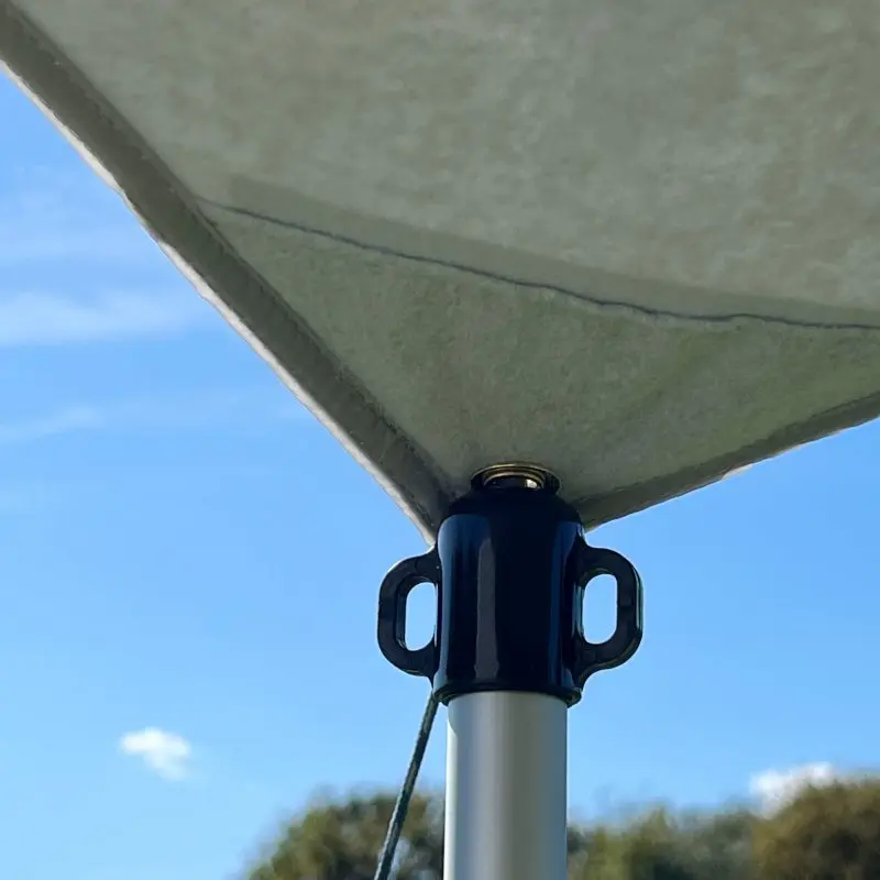 Close-up of your GEAR Caravan Thermo Tarp corner with durable aluminum-coated Oxford polyester, waterproof and UV80 sun protection, attached to a metal pole, outdoor setting with blue sky in the background.