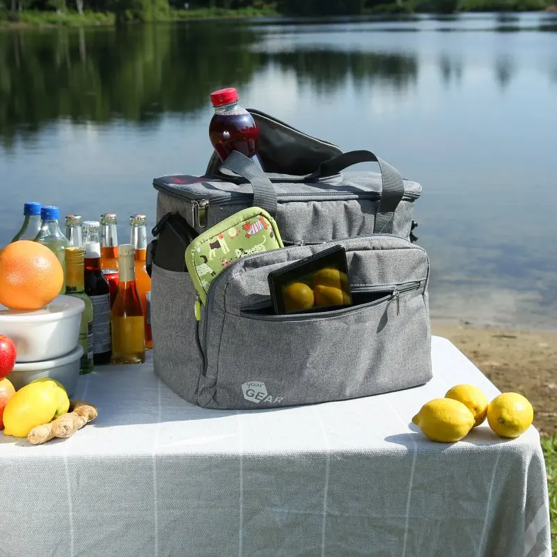 Large grey your GEAR foldable cooler bag Cavoli, 30 liters, with front pocket, zipper access, sturdy handles, and insulated lining, placed on a picnic table outdoors, surrounded by drinks and fruits.