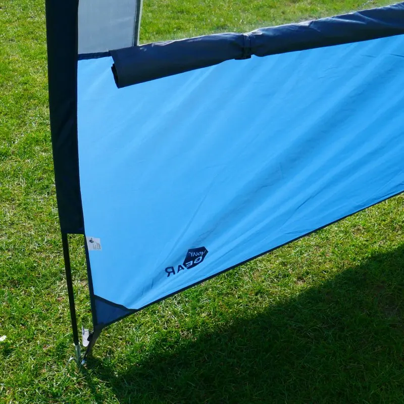 Blaues your GEAR Riviera 300 Vorzelt mit UV 50+ Schutz, auf Wiese aufgestellt. Sichtbar sind stabile Gestänge, das strapazierfähige Material und das Logo. Ideal als Sonnendach oder Wetterschutz für Wohnwagen und Wohnmobil.
