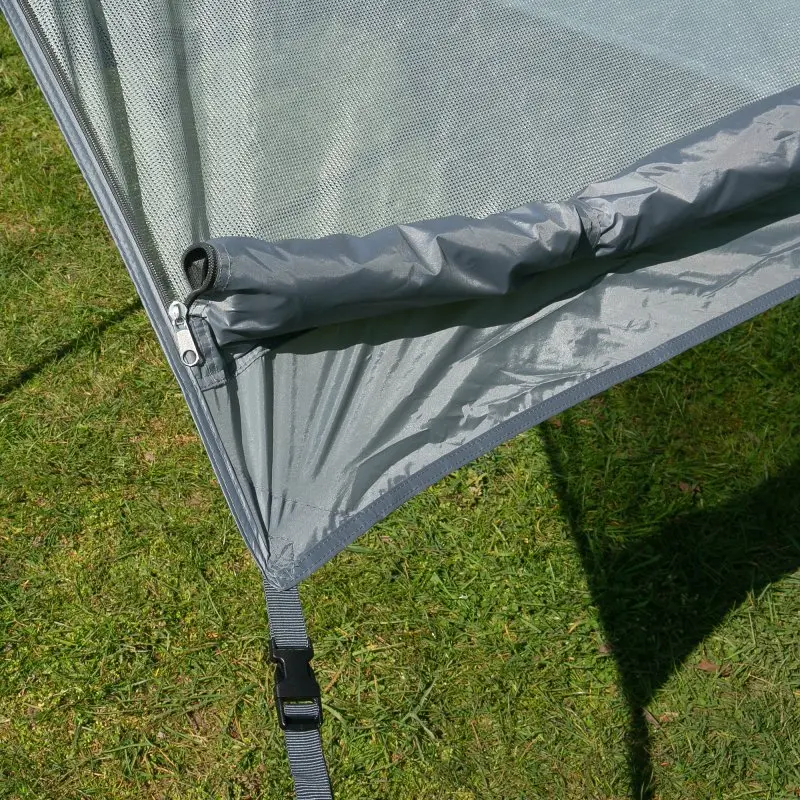 Close-up of your GEAR Sun + Rain Blocker side wall for campervan awnings, showing grey double-layered fabric with mesh sun protection, waterproof cover, zipper, and securing strap on grass background.