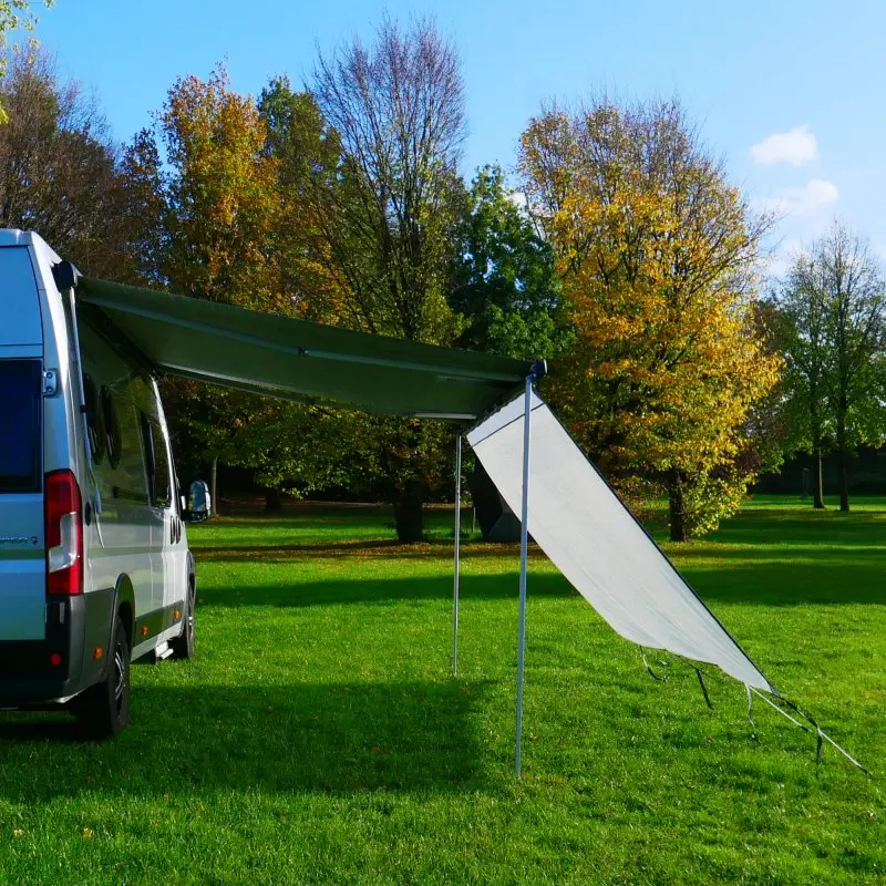 Vela frontal your GEAR Capri Sun Blocker de 2,8 x 2 m instalada en la marquesina de una furgoneta camper, ofreciendo sombra y protección solar en un entorno de camping al aire libre.