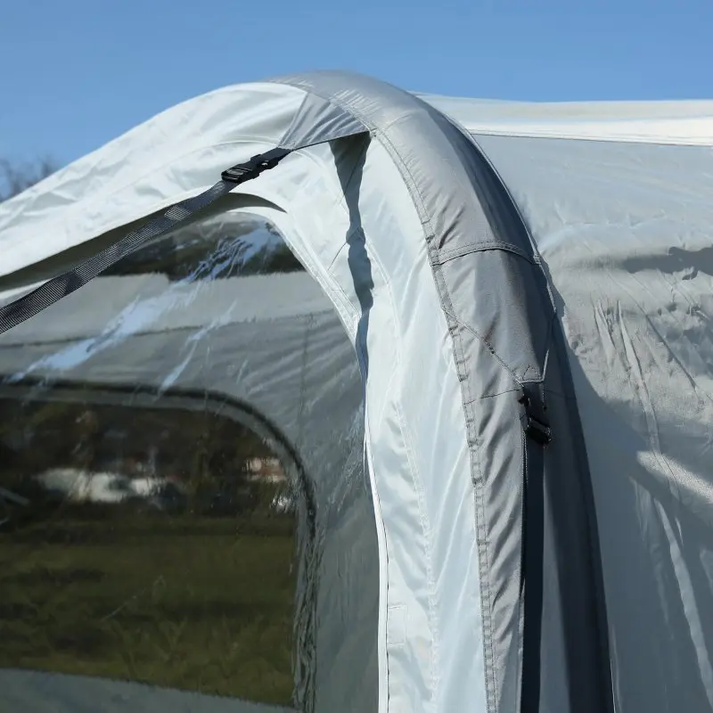 Dettaglio di una tenda gonfiabile grigia con finestra trasparente, ripresa all'aperto sotto un cielo azzurro.